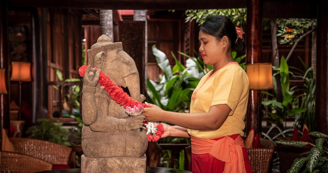 Angkor Village Hotel - Small Luxury Hotels Of The World Siem Reap Exteriér fotografie A woman in Thailand, wearing traditional Thai clothing, garlands a statue of the Hindu god Ganesha.